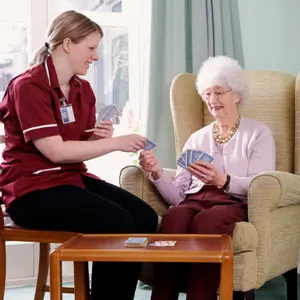 A nurse and an elderly woman playing cards