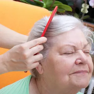 A woman is combing her hair with a red comb.