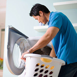 A man is loading clothes into the washing machine.