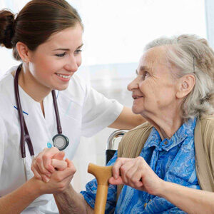 A nurse is holding the hand of an elderly woman.