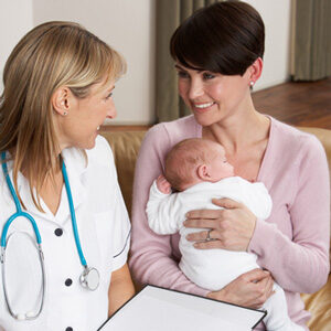 A woman holding a baby while talking to a doctor.