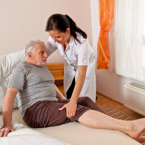 A nurse is helping an elderly man in bed.