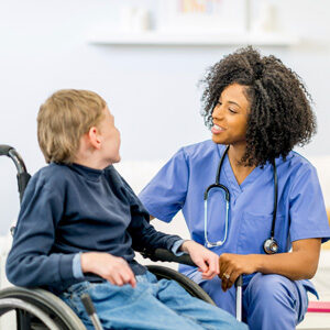 A nurse is talking to a boy in a wheelchair.