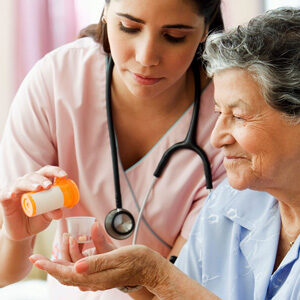 A nurse is showing an elderly woman how to use an inhaler.
